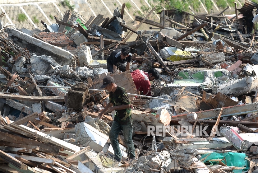 Warga memungut besi sisa bangunan usai gusuran di Bukit Duri, Jakarta, Kamis (29/9).