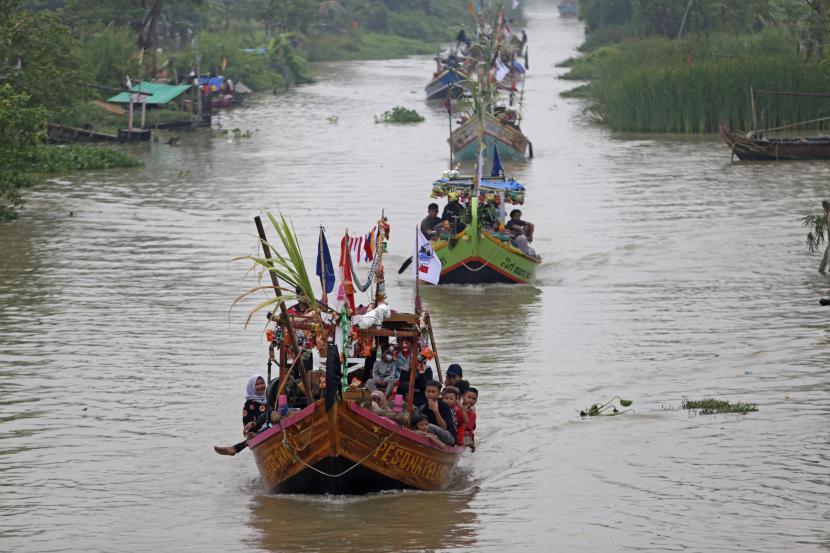 Warga menaiki perahu hias saat mengikuti Tradisi Nadran (pesta laut) di Sungai Cimanuk, Indramayu, Jawa Barat.