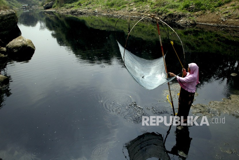 Warga mencari ikan di aliran Sungai Cileungsi yang berwarna hitam pekat akibat tercemar limbah di kawasan Bojong Kulur, Gunung Putri, Kabupaten Bogor, Jawa Barat, Senin (22/7/2019).