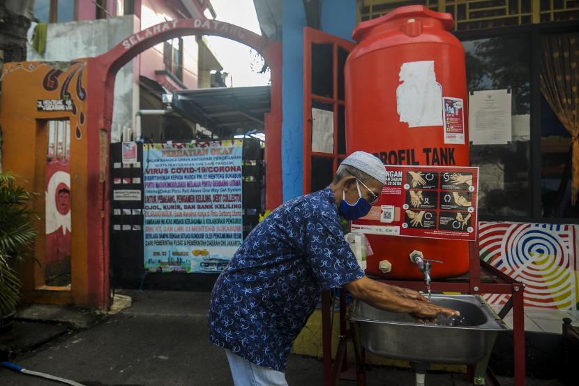 Warga mencuci tangan sebelum memasuki pemukiman saat pemberlakuan pembatasan kegiatan masyarakat (PPKM) skala mikro hari pertama di kawasan Menteng, Jakarta.