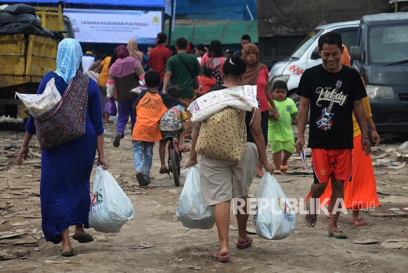 Warga mendapatkan sambako dari Lazis PLN yang dibagiakan di Kampung Empang, Kapuk Muara, Jakarta Utara, Jumat (31/3).