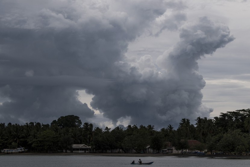 Warga mendayung sampan dengan latar belakang erupsi Gunung Anak Krakatau (GAK) di Pelabuhan Pulau Sebesi, Lampung Selatan, Lampung, Selasa (1/1/2019). 