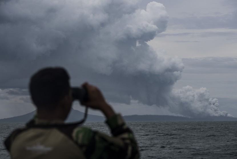 Warga mendayung sampan dengan latar belakang erupsi Gunung Anak Krakatau di Pelabuhan Pulau Sebesi, Lampung Selatan, Lampung, Selasa (1/1/2019). 