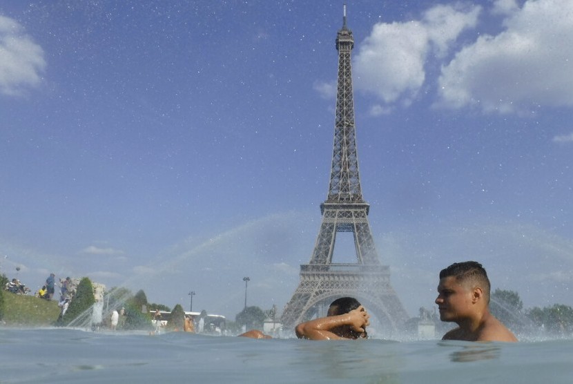 Warga mendinginkan diri di kolam air mancur Trocadero dengan latar belakang menara Eiffel di Paris, Prancis, Selasa (25/6). Menteri Kesehatan Prancis Francois Braun mengatakan, saat ini negaranya sudah memiliki sekitar 1.700 kasus monkeypox atau cacar monyet. 