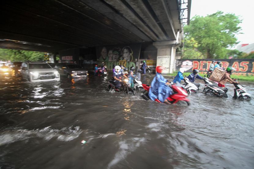Warga mendorong kendaraannya yang mogok saat melewati banjir di kawasan Jalan Raya Jati, Sidoarjo, Jawa Timur, Ahad (23/10/2022). Hujan deras yang mengguyur kawasan tersebut menyebabkan banjir sepanjang 200 meter dengan ketinggian mencapai 50 cm. 