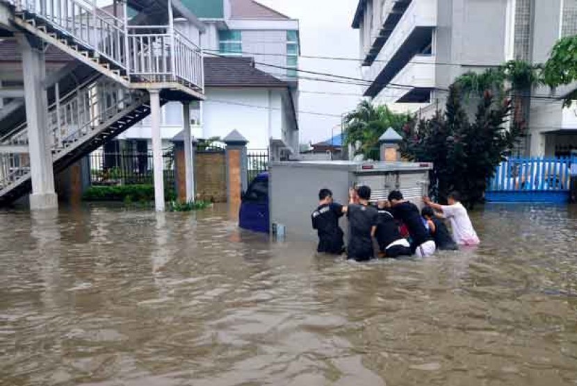 Warga mendorong mobil yang mogok di tengah banjir di Cempaka Putih, Jakarta. Pemkot Jakpus membangun empat embung di Cempaka Putih untuk mengatasi banjir.