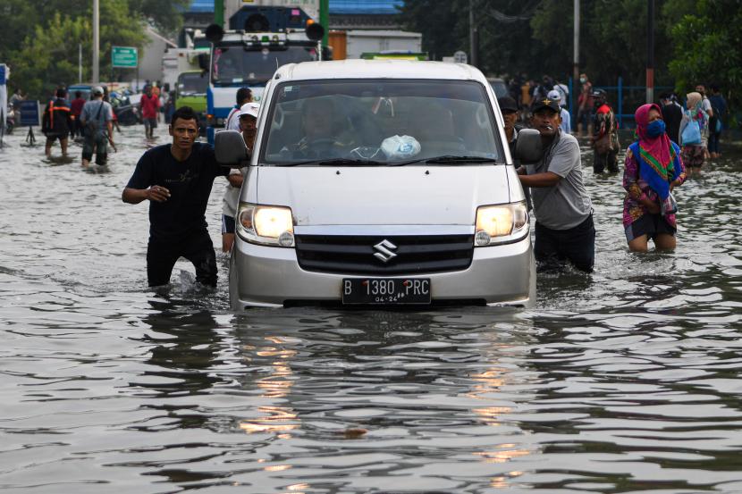 Warga mendorong mobil yang mogok saat melintasi banjir air rob (ilustrasi)