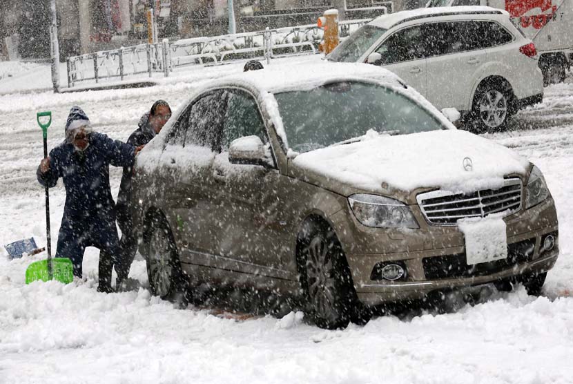  Warga mendorong mobil yang terdampar akibat hujan salju lebat di Tokyo.