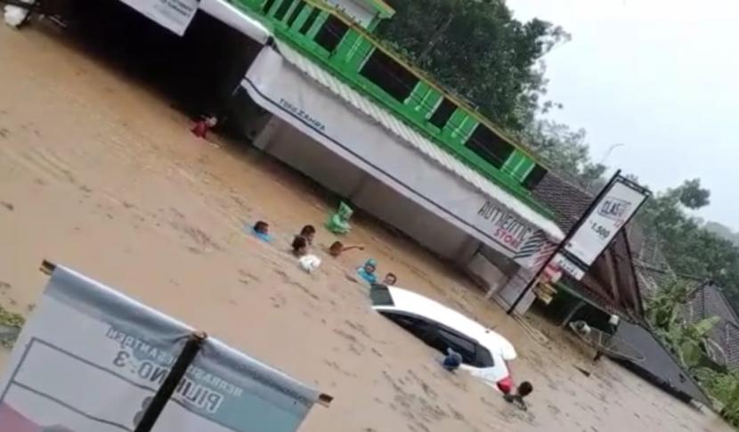Warga mendorong mobil yang terendam banjir di Kecamatan Bantarkalong, Kabupaten Tasikmalaya, Senin (12/10)