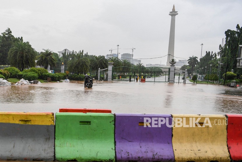 Warga mendorong motor melintasi banjir di kawasan Monas, Jalan Medan Merdeka Barat, Jakarta, Ahad (2/2/2020).