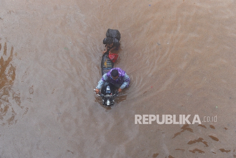 Warga mendorong motor untuk menerobos banjir di Jalan Raya Kalimalang, Bekasi Barat, Kota Bekasi. Ilustrasi