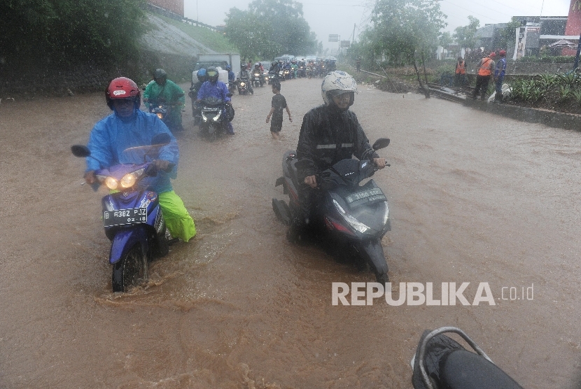 Warga mendorong motor untuk menerobos banjir di Jalan Raya Kalimalang, Bekasi Barat, Kota Bekasi, Senin (20/2).