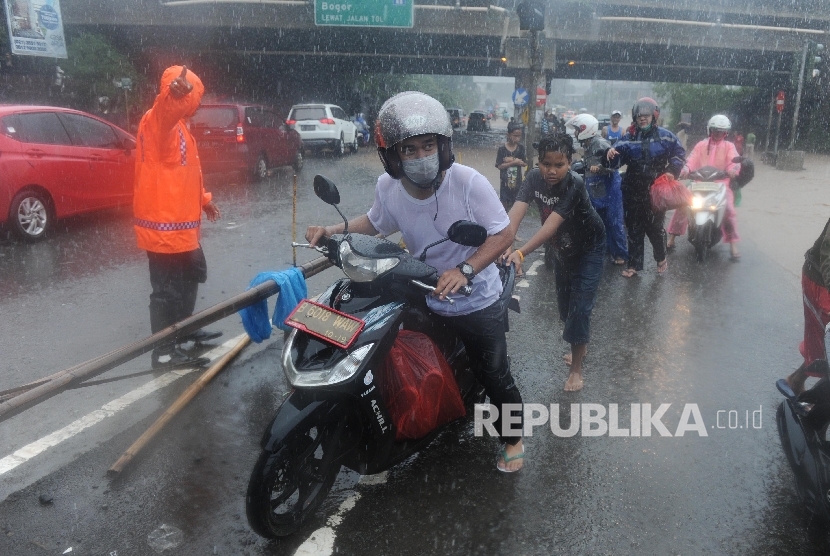 Warga mendorong motor untuk menerobos banjir di Jalan Raya Kalimalang, Bekasi Barat, Kota Bekasi, Senin (20/2).
