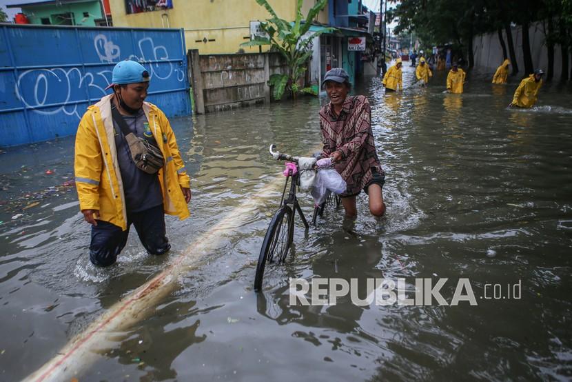 Warga mendorong sepeda melintasi banjir di Jalan Galeong, Karawaci, Kota Tangerang, Banten, Selasa (16/2/2021). Banjir setinggi hingga 80 cm tersebut disebabkan hujan deras dan luapan Kali Galeong. 