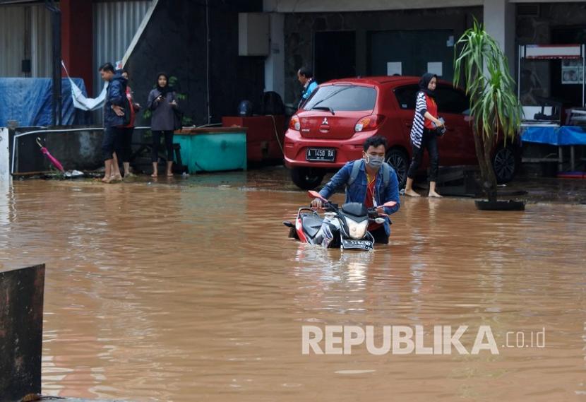 Warga mendorong sepeda motor yang mogok terendam banjir di Kotasari, Grogol, Cilegon, Banten, Senin (4/5/2020). 