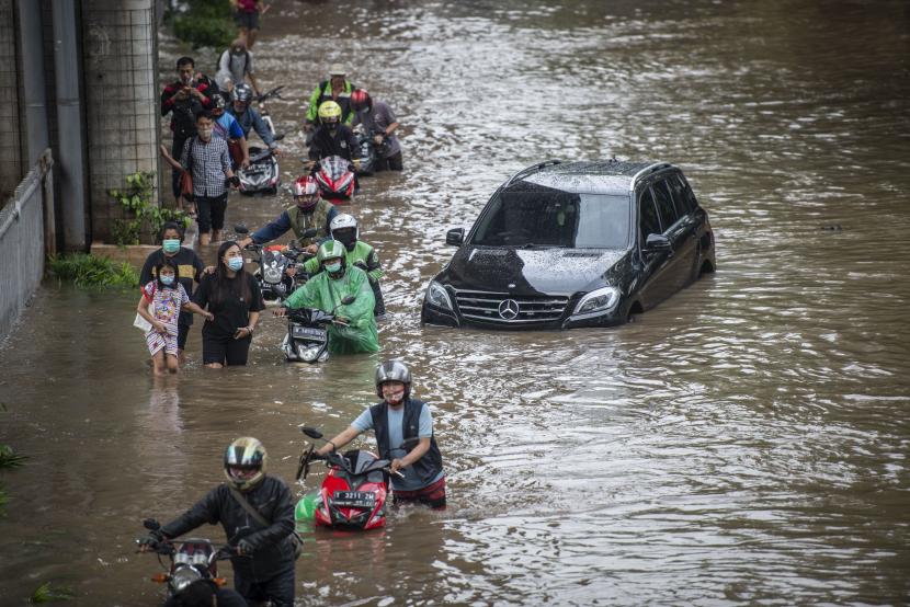 Warga mendorong sepeda motornya melintasi banjir di Jalan Kapten Tendean, Mampang Prapatan, Jakarta, Sabtu (20/2/2021). Banjir tersebut disebabkan karena curah hujan tinggi sejak Jumat (19/2) malam. 