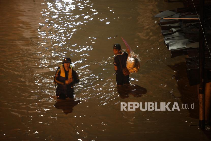 Warga menerobos banjir di kawasan Cililitan, Jakarta, Senin (5/2) malam. Banjir yang merendam kawasan tersebut akibat luapan Kali Ciliwung yang merupakan kiriman dari Bendung Katulampa, Bogor. 