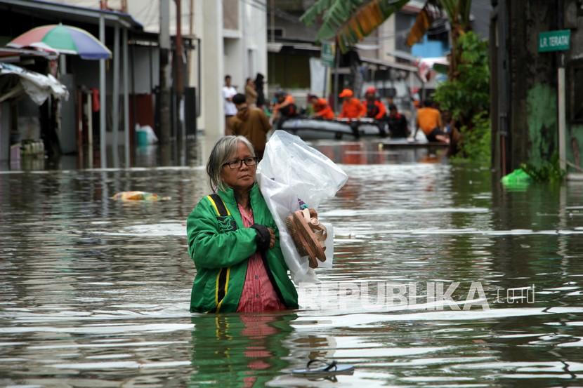 Warga menerobos banjir di Kelurahan Batua, Makassar, Sulawesi Selatan, Selasa (7/12/2021). Ratusan rumah di daerah itu terendam banjir akibat curah hujan yang tinggi dan sebagian warga sudah mulai mengungsi.