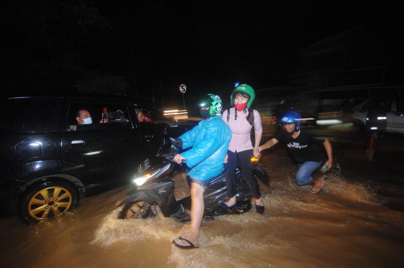 Warga menerobos banjir di salah satu ruas jalan di Kota Manado, Sulawesi Utara, Jumat (22/1/2021). Curah hujan dengan intensitas tinggi selama sekitar tiga jam mengakibatkan sejumlah daerah tergenang air.