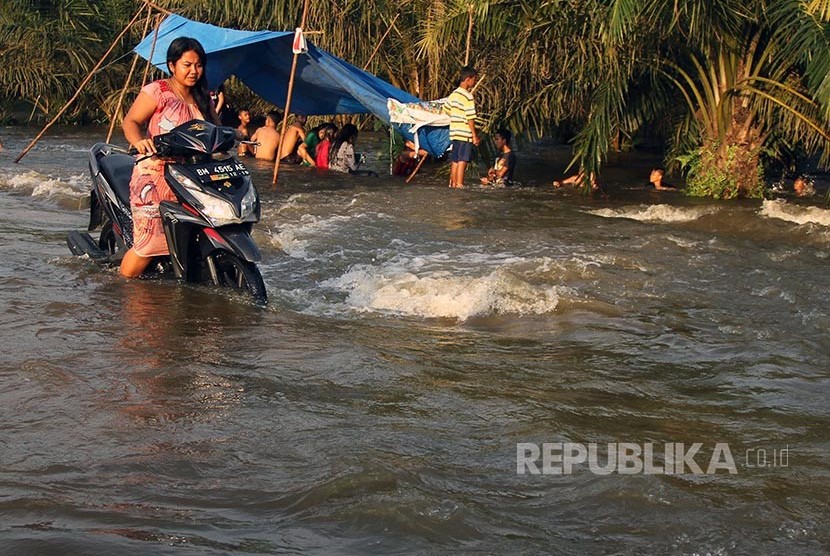 Warga menerobos banjir luapan Sungai Kampar yang merendam badan jalan di Desa Buluhcina, Kampar, Riau, Rabu (8/3). Meluapnya Sungai Kampar membuat ratusan rumah warga terendam