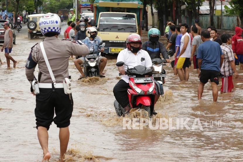 Warga menerobos banjir yang menggenangi jalan di Banyuwangi. 