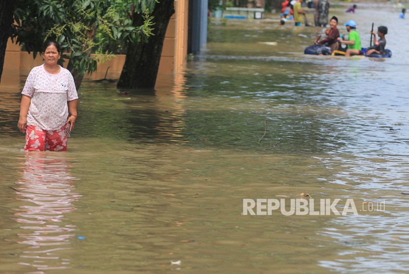 Warga menerobos banjir yang merendam desa Gunungjati, Cirebon, Jawa Barat, Ahad  (11/3). 