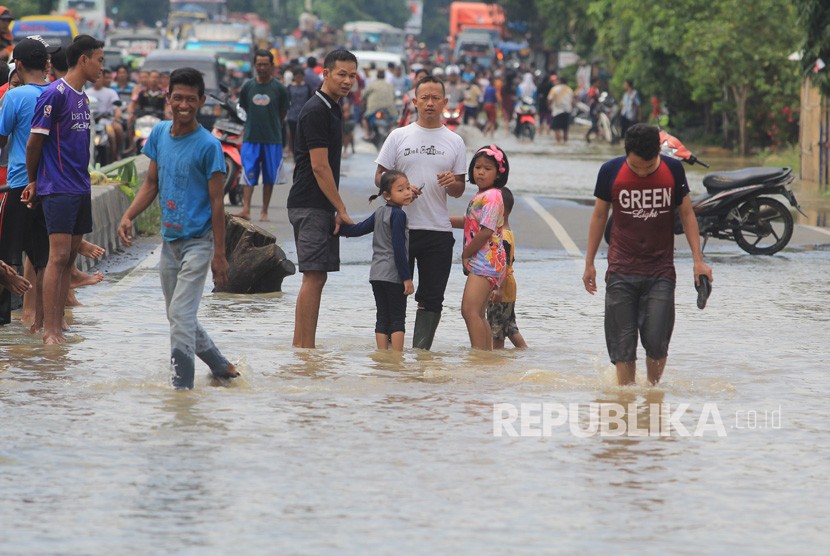 Warga menerobos banjir yang merendam desa Gunungjati, Cirebon, Jawa Barat, Ahad (11/3).