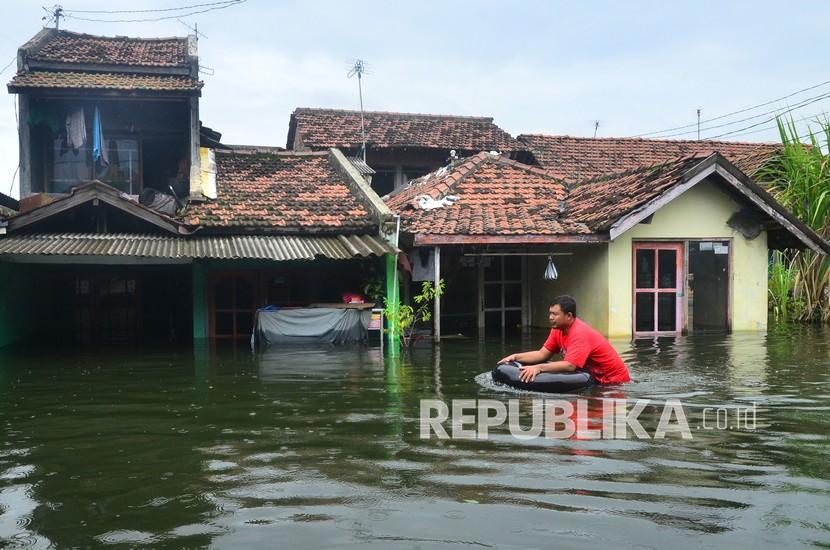 Warga menerobos jalan yang tergenang banjir, di Dukuh Tanggulangin, Desa Jati Wetan, Jati, Kudus, Jawa Tengah, Senin (8/2/2021). Menurut data dari Badan Penanggulangan Bencana Daerah (BPBD) setempat, banjir dengan ketinggian hingga 170 centimeter yang merendam 13 desa di kecamatan Mejobo, Jati dan Undaan lebih dari sepekan akibat curah hujan tinggi serta meluapnya sungai Lusi dan Wulan itu menyebabkan sebanyak 17.614 jiwa terdampak dan 4.420 rumah terendam serta 576 warga mengungsi. 