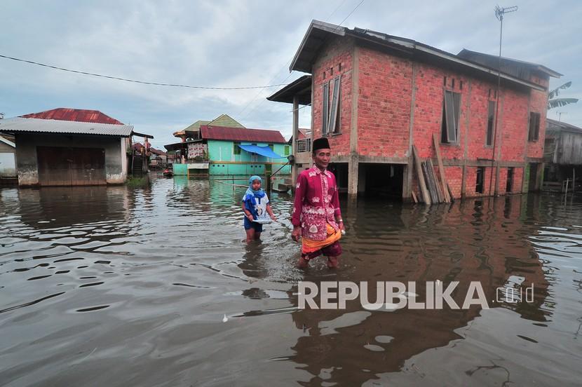 Warga menerobos jalan yang tergenang banjir luapan Sungai Batanghari di Legok, Danau Sipin, Jambi, Kamis (11/11/2021). Seratusan rumah di daerah itu terendam banjir luapan Sungai Batanghari yang terus meninggi sejak tiga hari terakhir. 