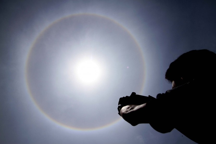 Warga mengabadikan fenomena Halo Matahari berbentuk cincin terlihat di atas langit kota Lhokseumawe, Aceh, , Kamis (30/3). 