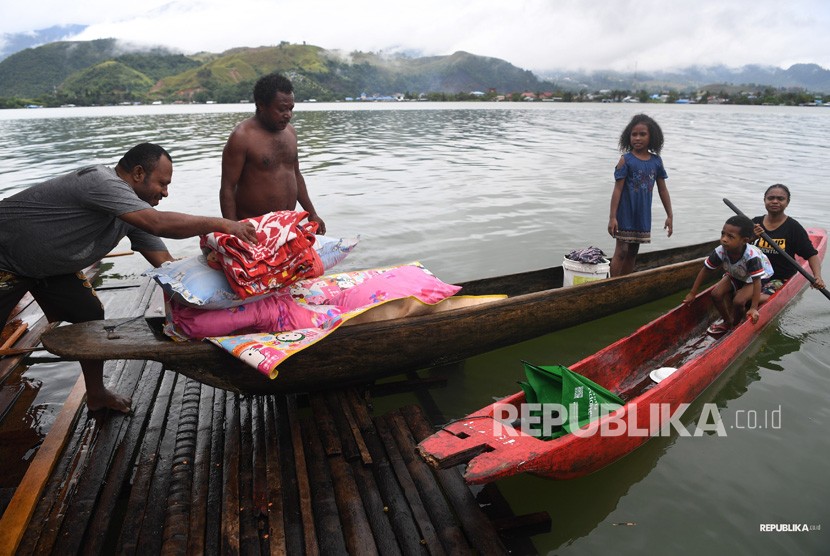 Warga mengamankan barang berharga miliknya dari rumahnya yang dilanda banjir bandang di kawasan Danau Sentani, Sentani, Jayapura, Papua, Selasa (19/3/2019). 