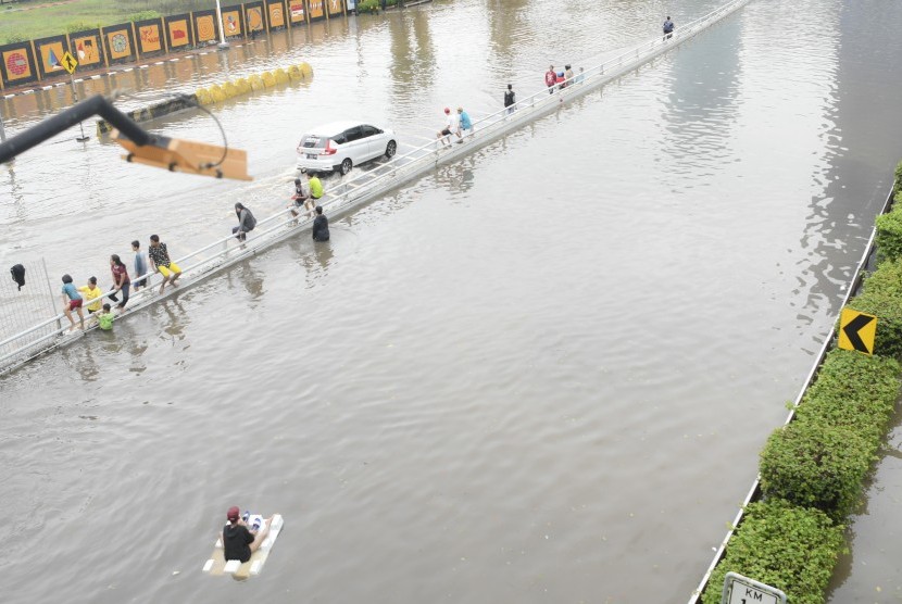 Sejumlah bocah bermain saat banjir yang merendam Jalan Letjen S Parman dan tol dalam kota di Jakarta Barat, Rabu (1/1/2020).