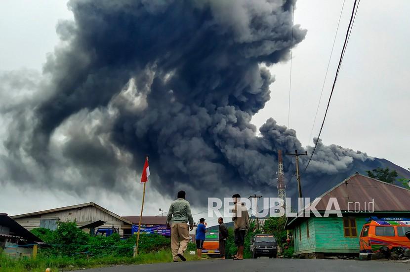 Warga mengamati Gunung Sinabung menyemburkan material vulkanik saat erupsi (ilustrasi)