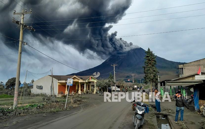 Warga mengamati Gunung Sinabung menyemburkan material vulkanik saat erupsi di Desa Sigarang garang, Karo, Sumatera Utara, Jumat (14/8/2020). 