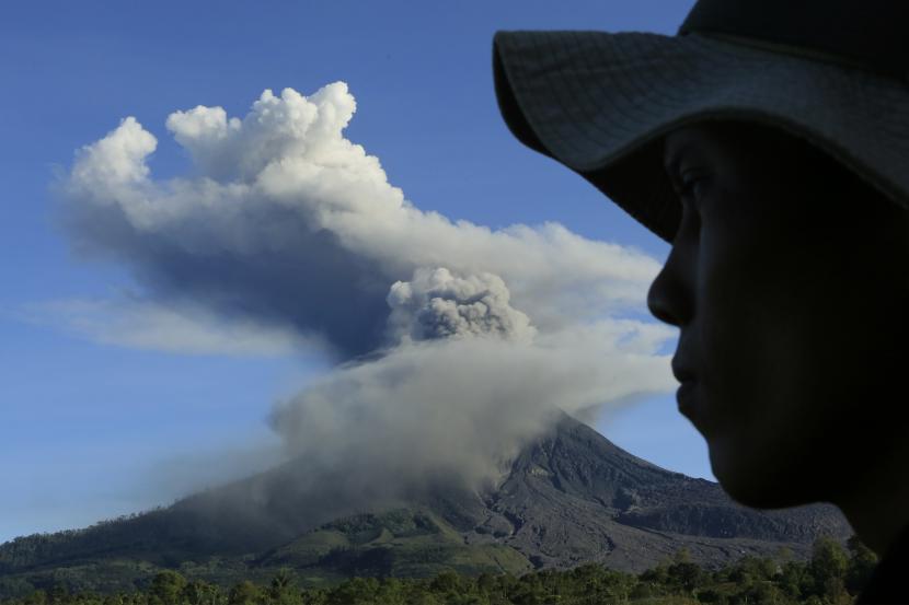 Warga mengamati Gunung Sinabung yang menyemburkan material vulkanik saat erupsi (ilustrasi)