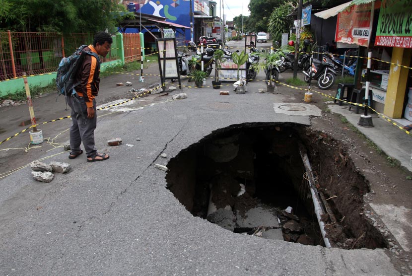 Warga mengamati jalan yang ambles di Jl. Babaran, Yogyakarta, Ahad (22/12).