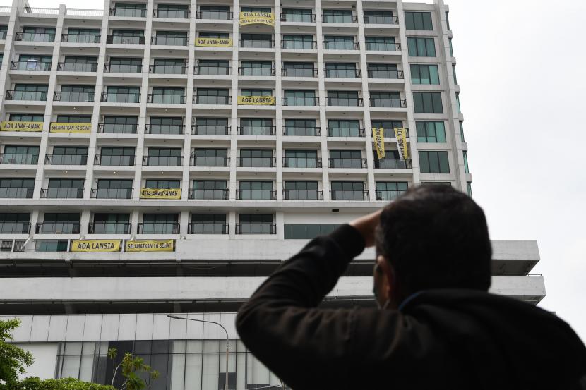 Warga mengamati spanduk bertuliskan penolakan atas penggunaan rumah sakit darurat COVID-19 yang terpasang di Lippo Plasa, Mampang, Jakarta, Ahad (5/4/2020). Aksi tersebut sebagai bentuk kekhawatiran penghuni apartemen Nine Residence yang membuat mereka berada dalam zona merah COVID-19.