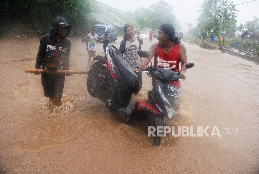 Warga mengangkat motor untuk menerobos banjir di Jalan Raya Kalimalang, Bekasi Barat, Kota Bekasi, Senin (20/2).