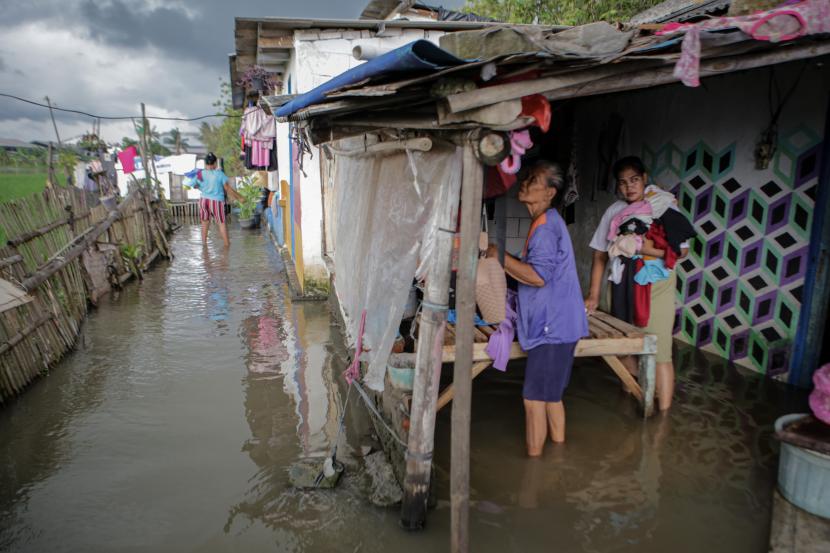 Warga mengangkat pakaian di tengah banjir di Pakuhaji, Kabupaten Tangerang, Banten. Pemkab Tangerang akan mengeruk saluran-saluran air di Pakuhaji untuk mencegah banjir.