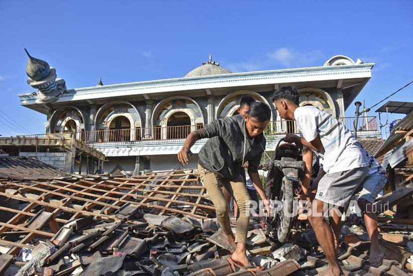 Warga mengangkat sepeda motornya dari reruntuhan rumah pascagempa di Desa Wadon, Kecamatan Gunungsari, Lombok Barat, NTB, Senin (6/8).