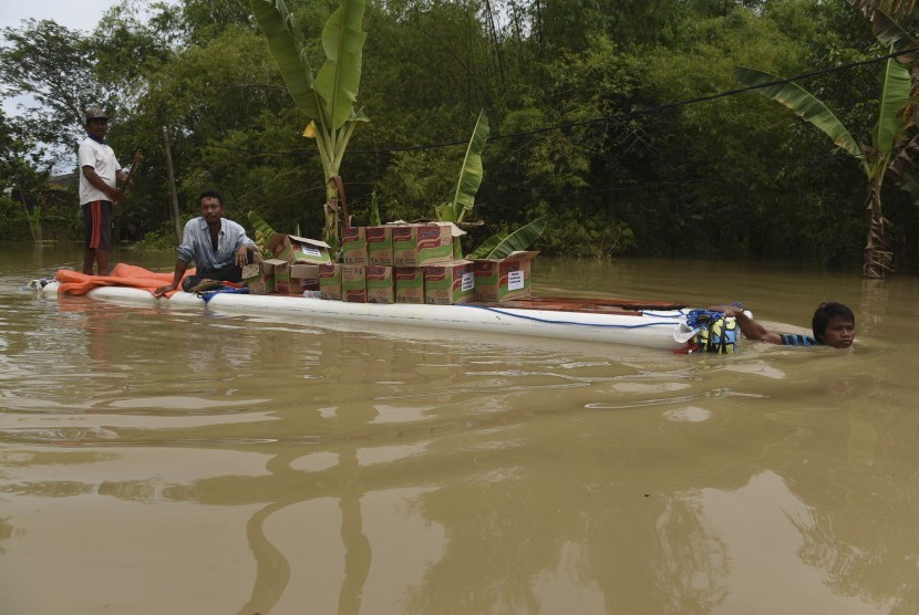 Warga mengangkut bantuan sembako di atas rakit melintasi banjir di Baureno, Bojonegoro, Jawa Timur, Jumat (2/12). 