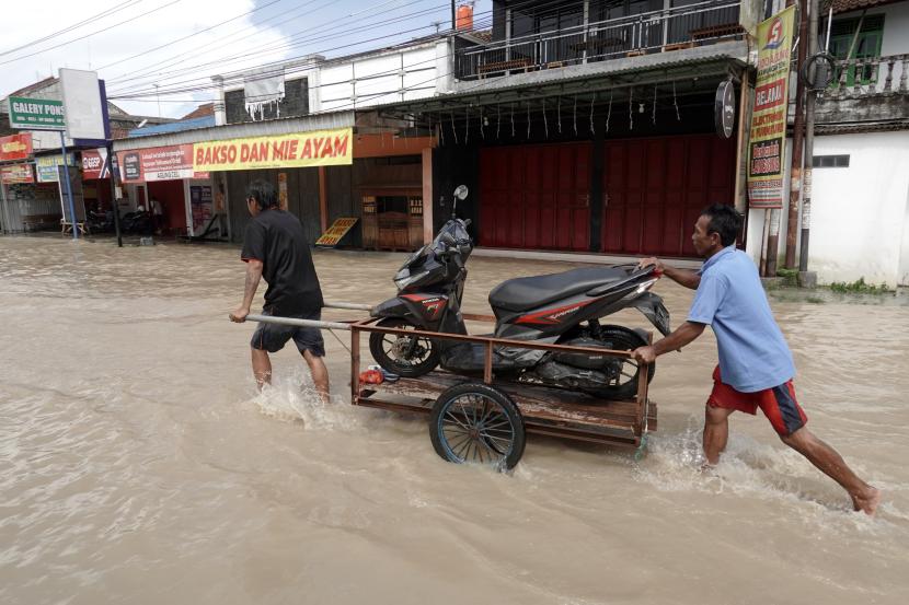 Warga mengangkut motor menggunakan gerobak melewati genangan banjir di Desa Kawunganten, Cilacap, Jateng.