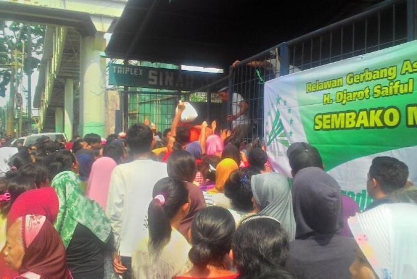 Warga mengantre dalam acara sembako murah yang digelar di Jalan Ngurah Rai, Kp. Sumur, Klender, Jakarta Timur, Jumat (14/4). 