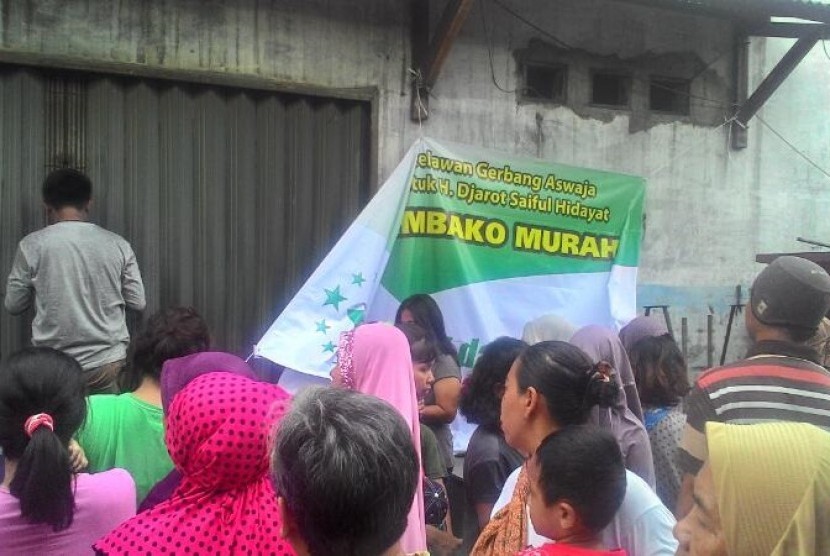 Warga mengantre dalam acara sembako murah yang digelar di Jalan Ngurah Rai, Kp. Sumur, Klender, Jakarta Timur, Jumat (14/4).
