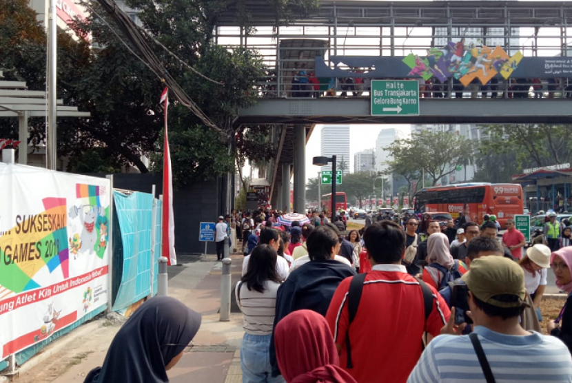 Warga mengantre untuk menggunakan JPO Halte GBK, Ahad (2/8).