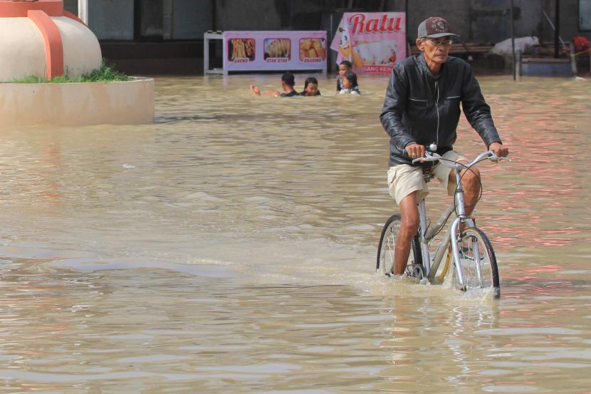 Warga mengayuh sepeda melewati banjir di Indramayu, Jawa Barat, Selasa (9/2/). Pemerintah Kabupaten Indramayu menetapkan status tanggap darurat banjir hingga Rabu (17/2) mendatang karena daerah yang terdampak banjir meluas. 