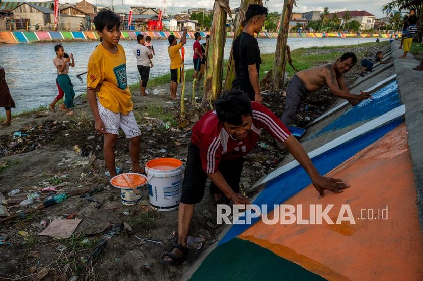 Warga mengecat tanggul bantaran Sungai Palu di Kelurahan Ujuna, Palu, Sulawesi Tengah, Senin (20/9/2021). BPS mencatat terjadi kenaikan angka kemiskinan di Sulawesi.