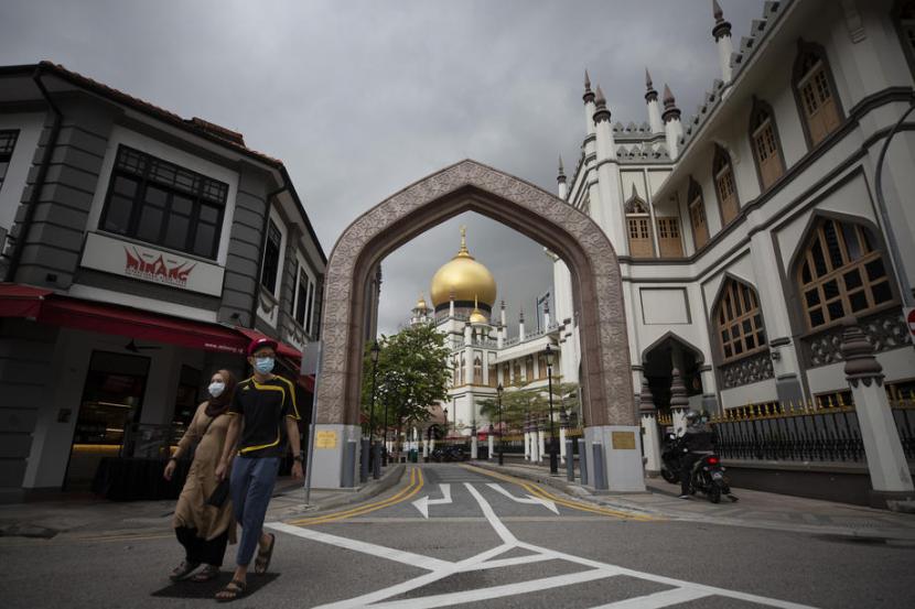 Warga mengenakan masker melintas di salah satu sudut Singapura, (24/4). Kementerian Kesehatan Singapura mencatat total infeksi Covid-19 mencapai 23.832. Ilustrasi.