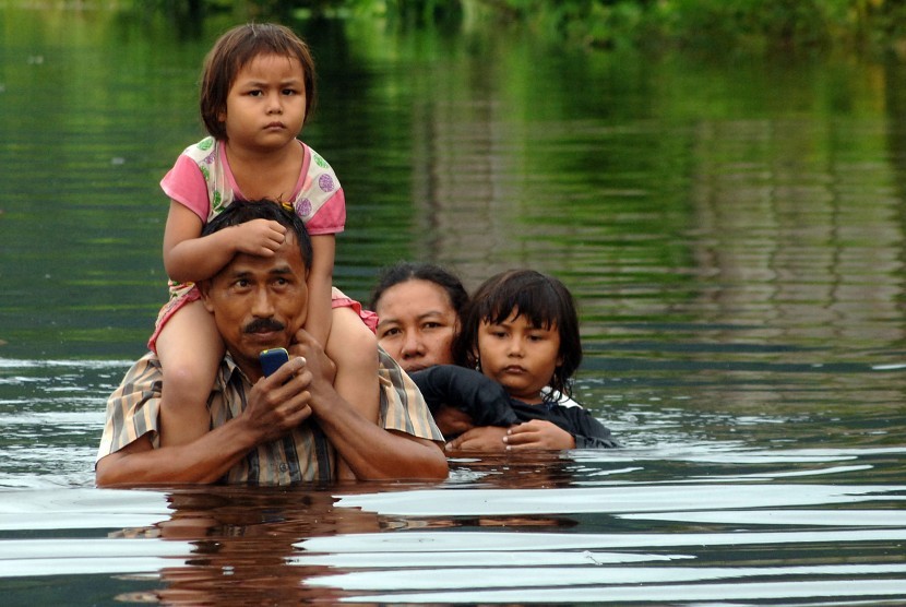 Warga mengevakuasi keluarganya melewati banjir yang merendam kawasan Batipuhpanjang, Kototangah, Padang, Sumatera Barat, Selasa (22/3).