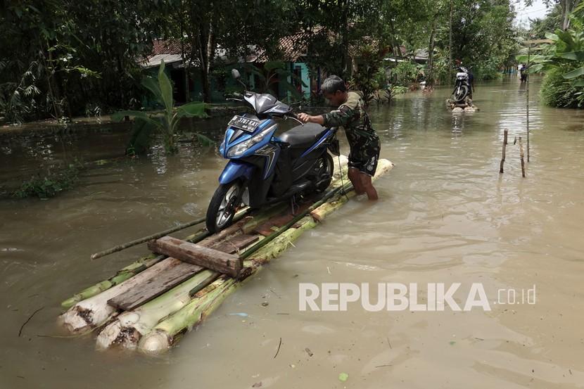 Warga mengevakuasi kendaraan bermotor menggunakan rakit darurat akibat banjir di  Banyumas, Jateng. 